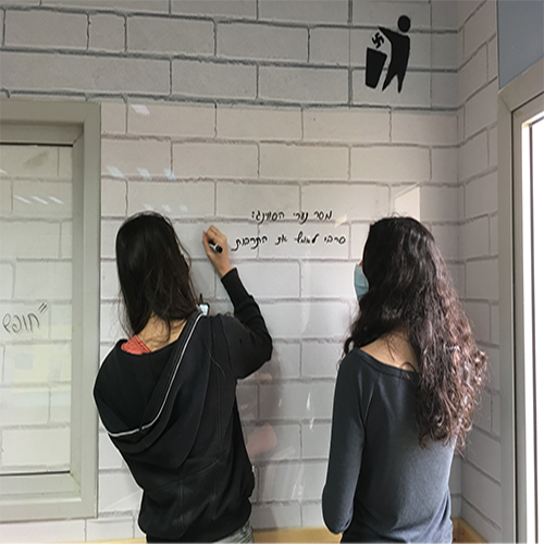 שתי תלמידות כותבות על קיר יעודי